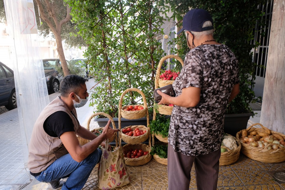 A volunteer helping an elderly woman to get what she needs to cook and eat.